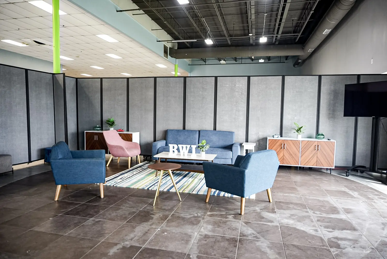 Completed employee lounge with sofas, armchairs, a rug and a wall mounted screen